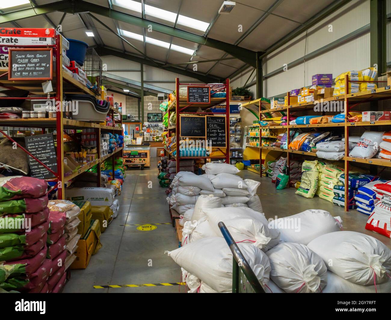 Interior of a farm shop in North Yorkshire with fresh vegetables milk and bottled drinks and food for farm animals and wild birds pigs pigeons poultry Stock Photo
