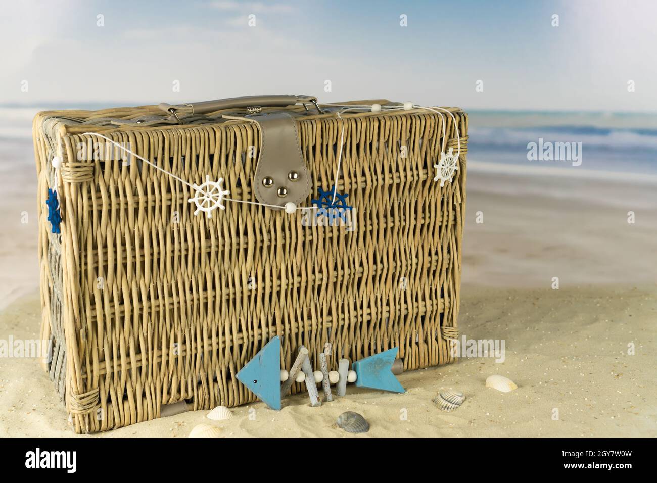 Old wicker basket with maritime decoration on the beach, blue sky