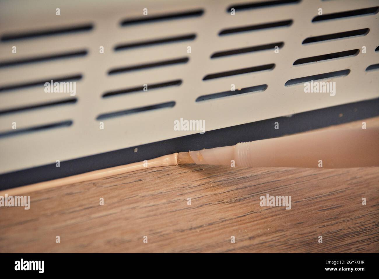 Applying brown silicone sealing on laminate flooring and plinth with