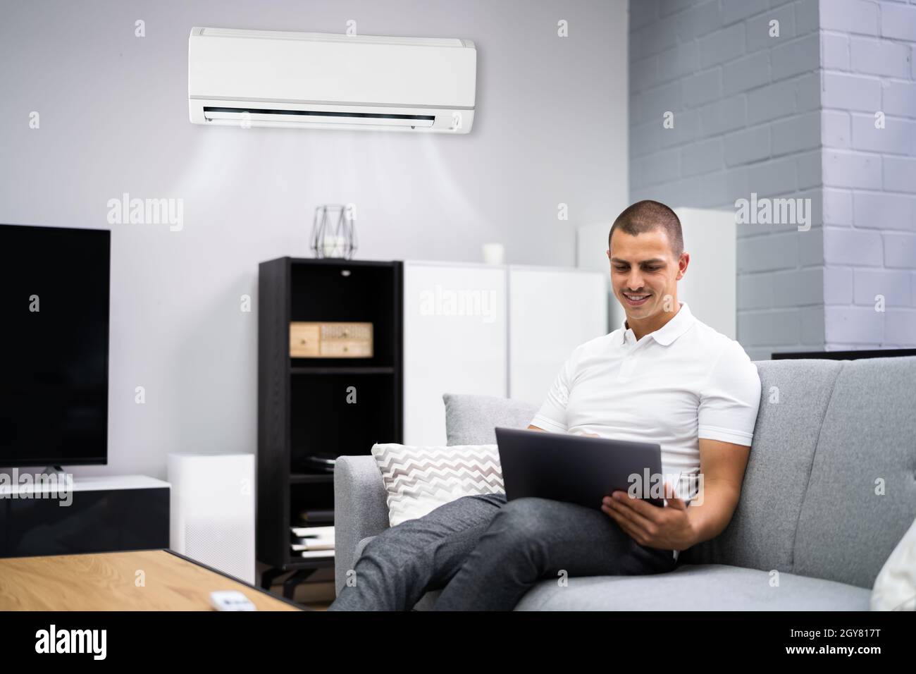 Man Using Ac Young Happy Man Sitting On Couch Using Air Conditioner At Home Stock ...
