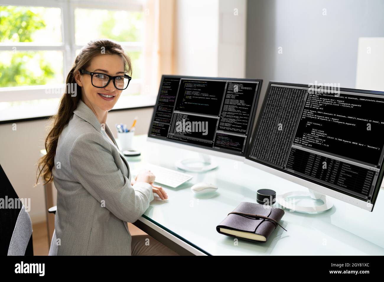 Programmer Woman Coding On Multiple Computer Screens Stock Photo - Alamy
