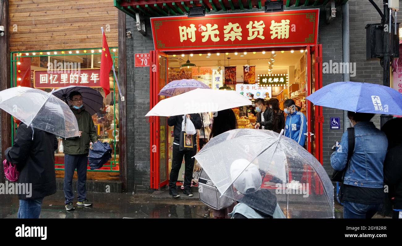 Beijing, China. 6th Oct, 2021. People walk past a shop at the Nanluoguxiang Lane during the week-long National Day holiday in Beijing, capital of China, Oct. 6, 2021. Credit: Li Xin/Xinhua/Alamy Live News Stock Photo
