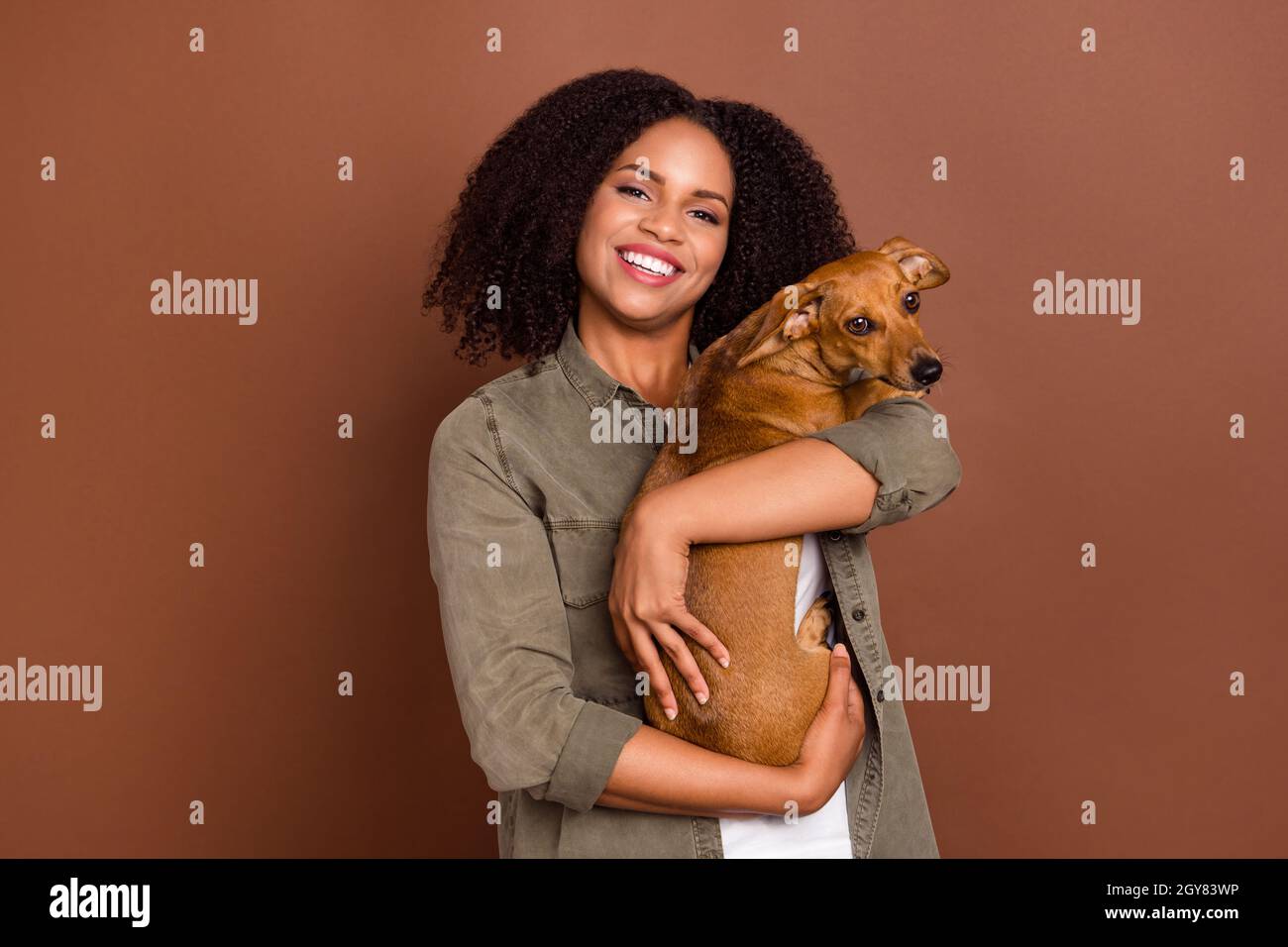 Photo of cute millennial brunette lady hold dog wear shirt isolated on brown color background Stock Photo