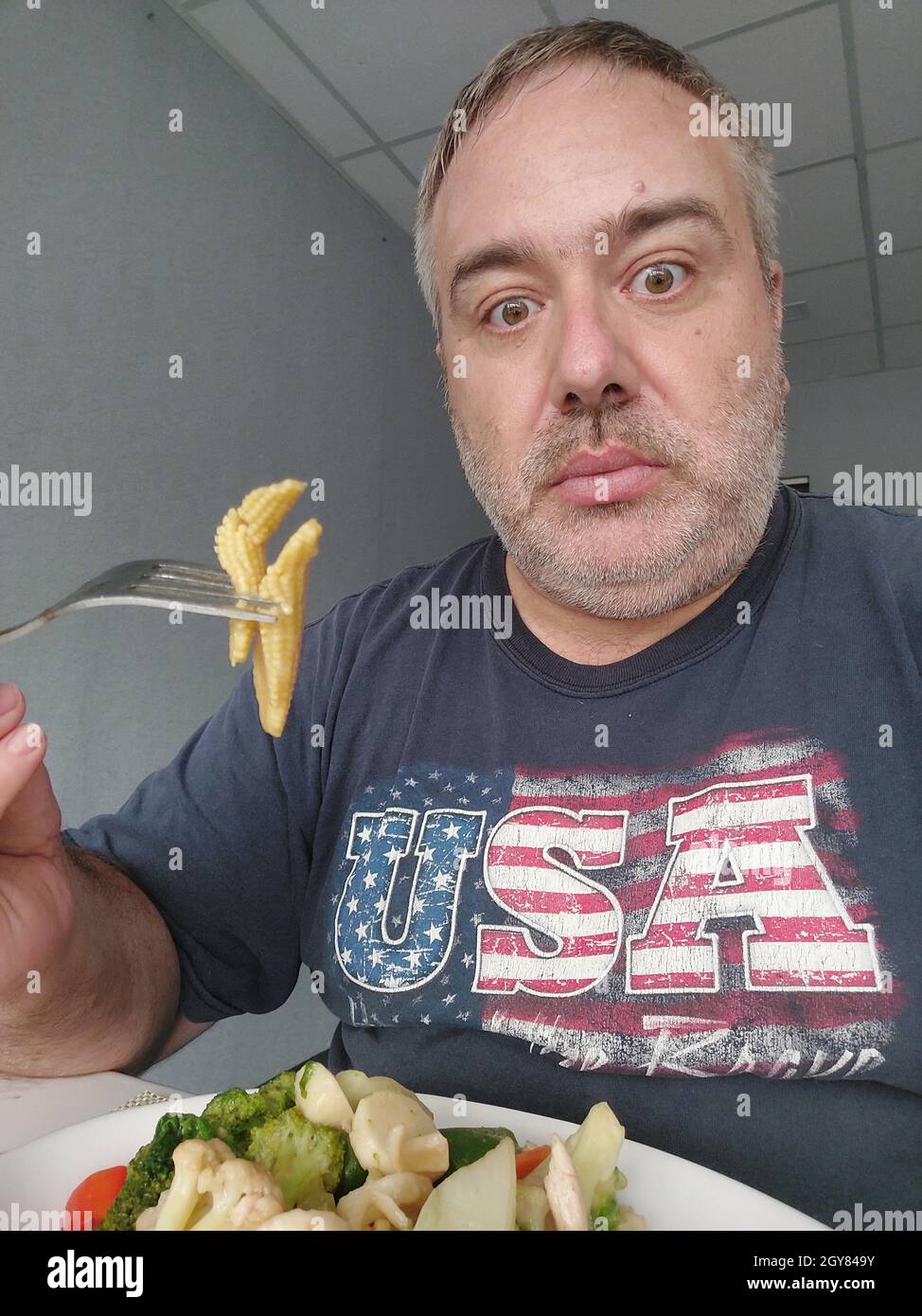 Fat American Man Eating Baby Corn Stock Photo