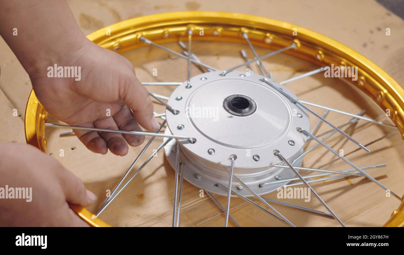Technician man working motorcycle wheel has spokes weave up on mechanic