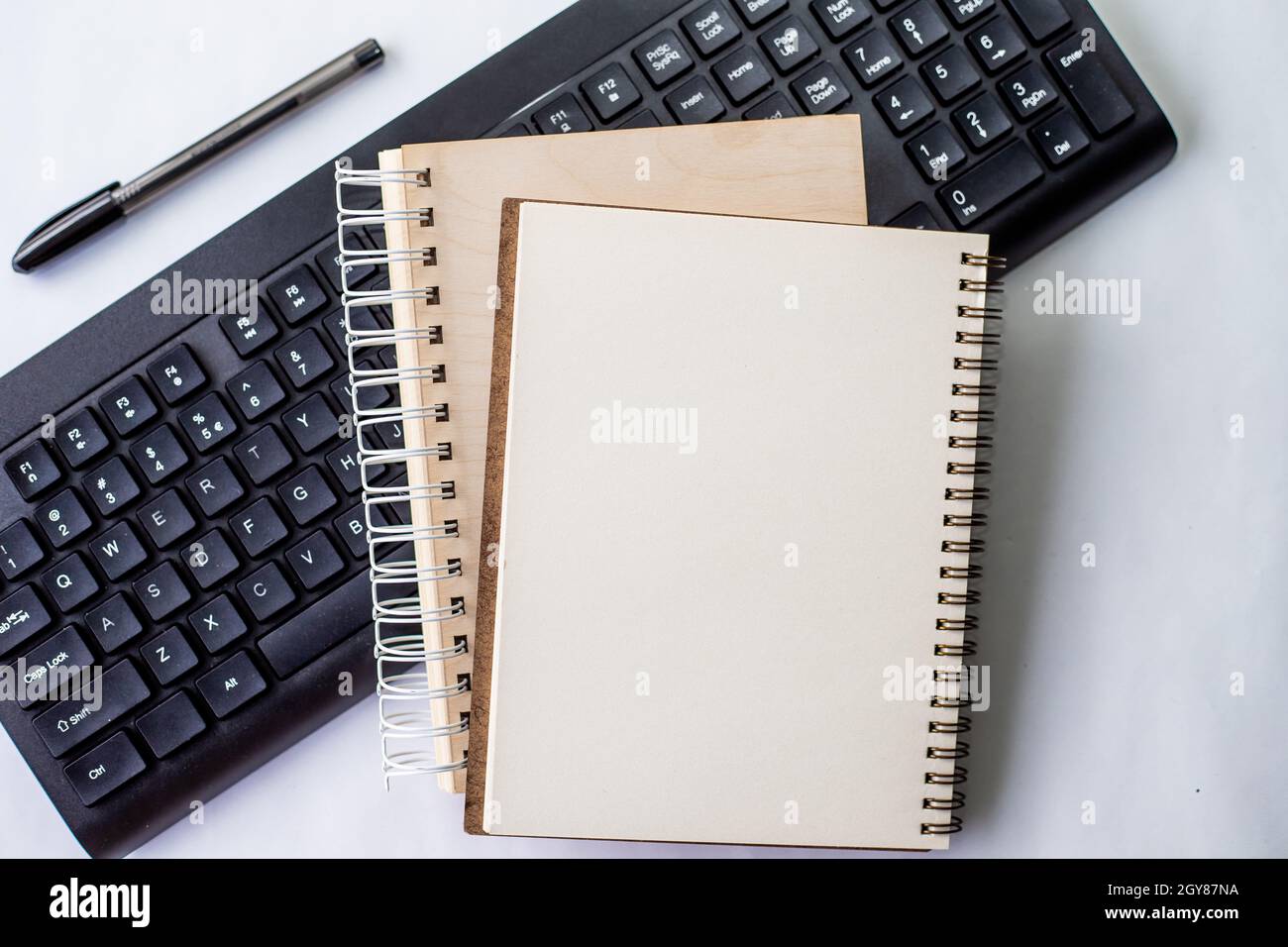 Two Plain Lined Spiral Notebooks With Pen And Keyboard On Table. Stock Photo