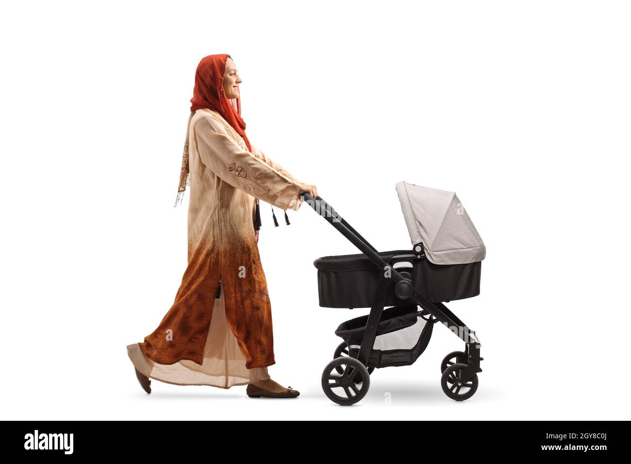 Full length profile shot of a woman wearing a hijab and pushing a baby stroller isolated on white background Stock Photo
