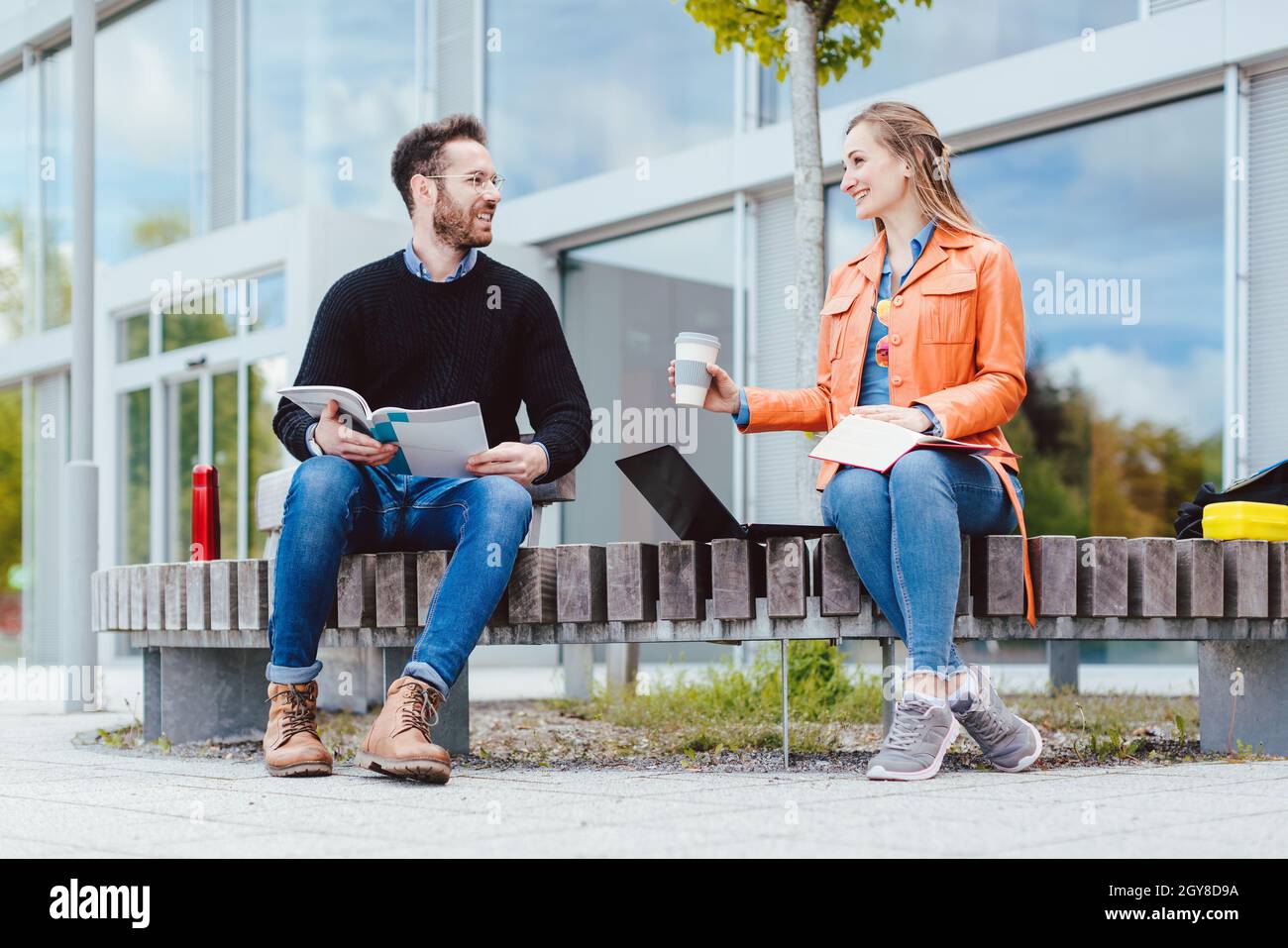 Man and woman student chatting on university campus in front of main building Stock Photo