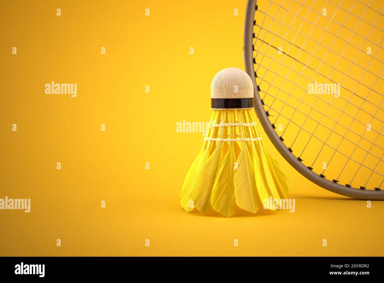 Badminton feather shuttlecock near badminton racket over a yellow