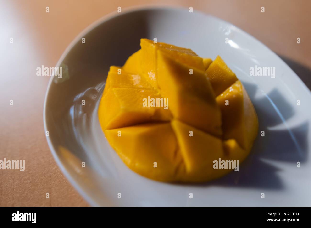 Diced mango on white plate above brown table Stock Photo
