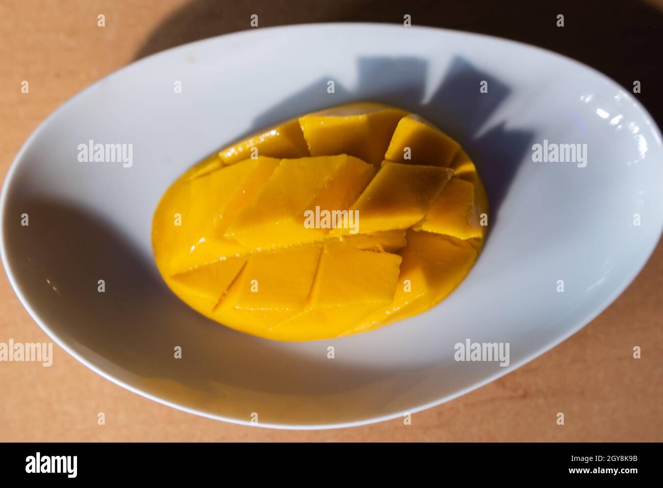 Diced mango on white plate above brown table Stock Photo