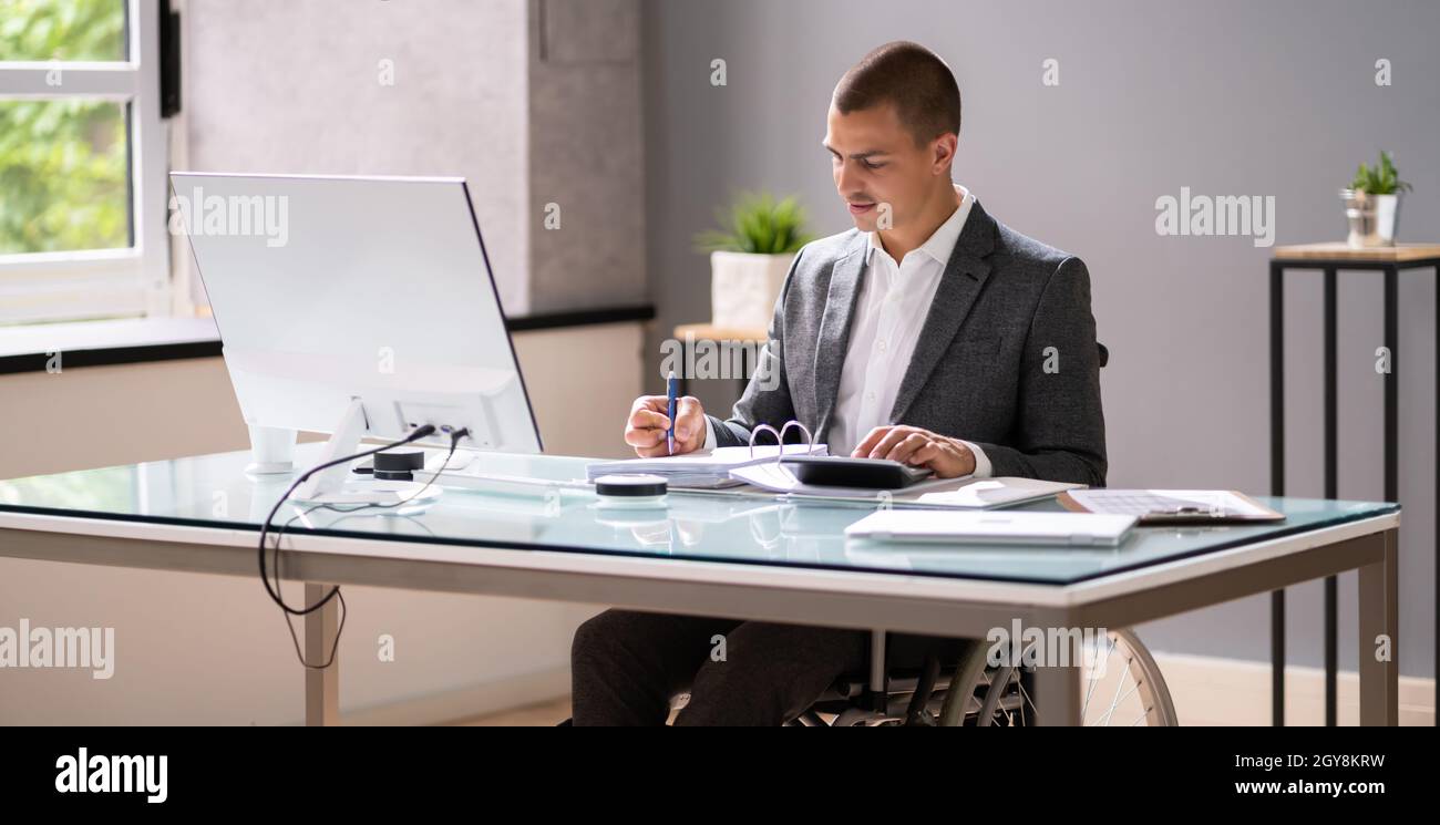 Disabled Accountant In Wheelchair Working Using Computer Stock Photo