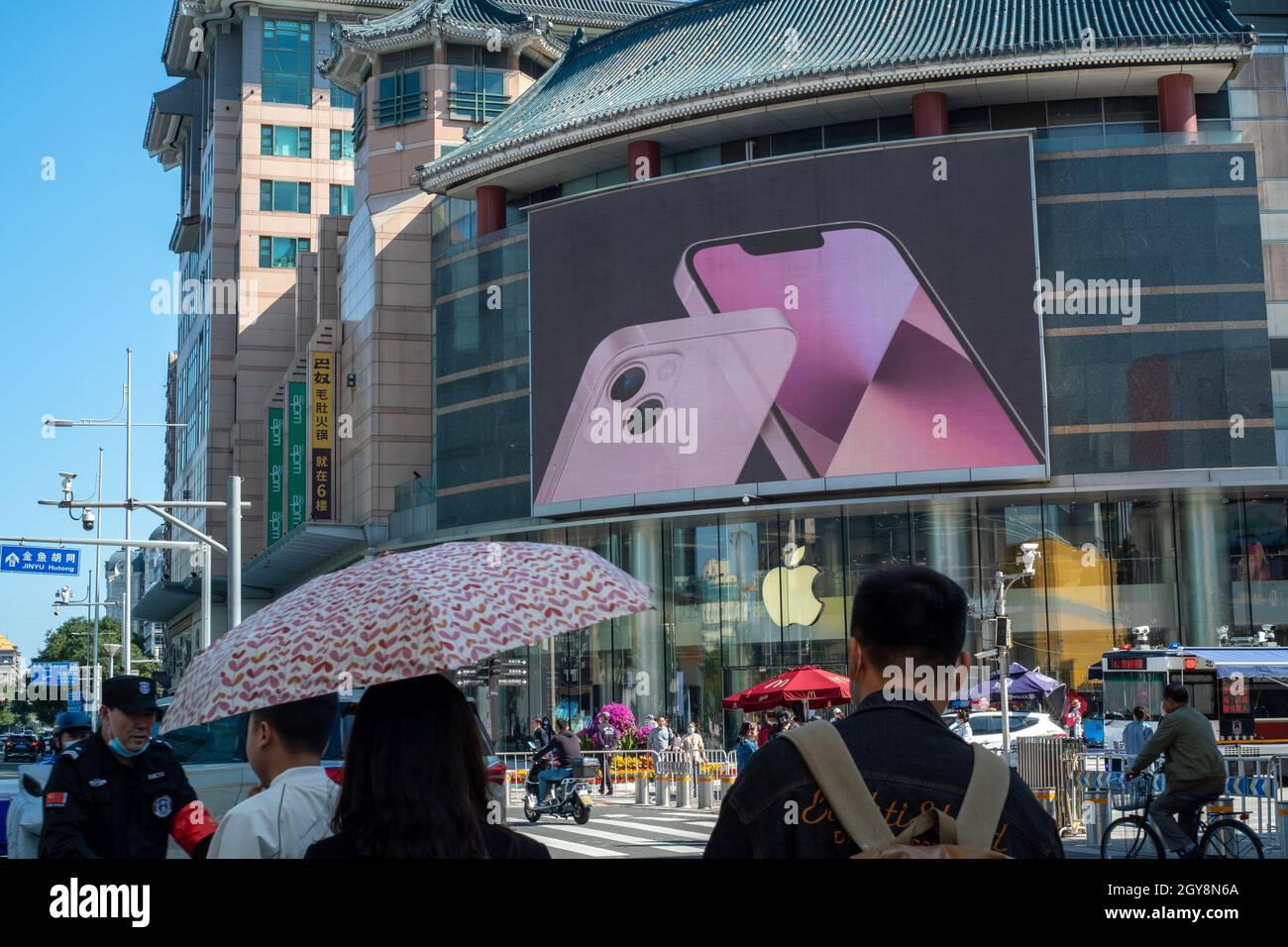 People walk past an apple store in Wangfujing with iPhone 13 series advertisement on a big screen in Beijing, China. 07-Oct-2021 Stock Photo