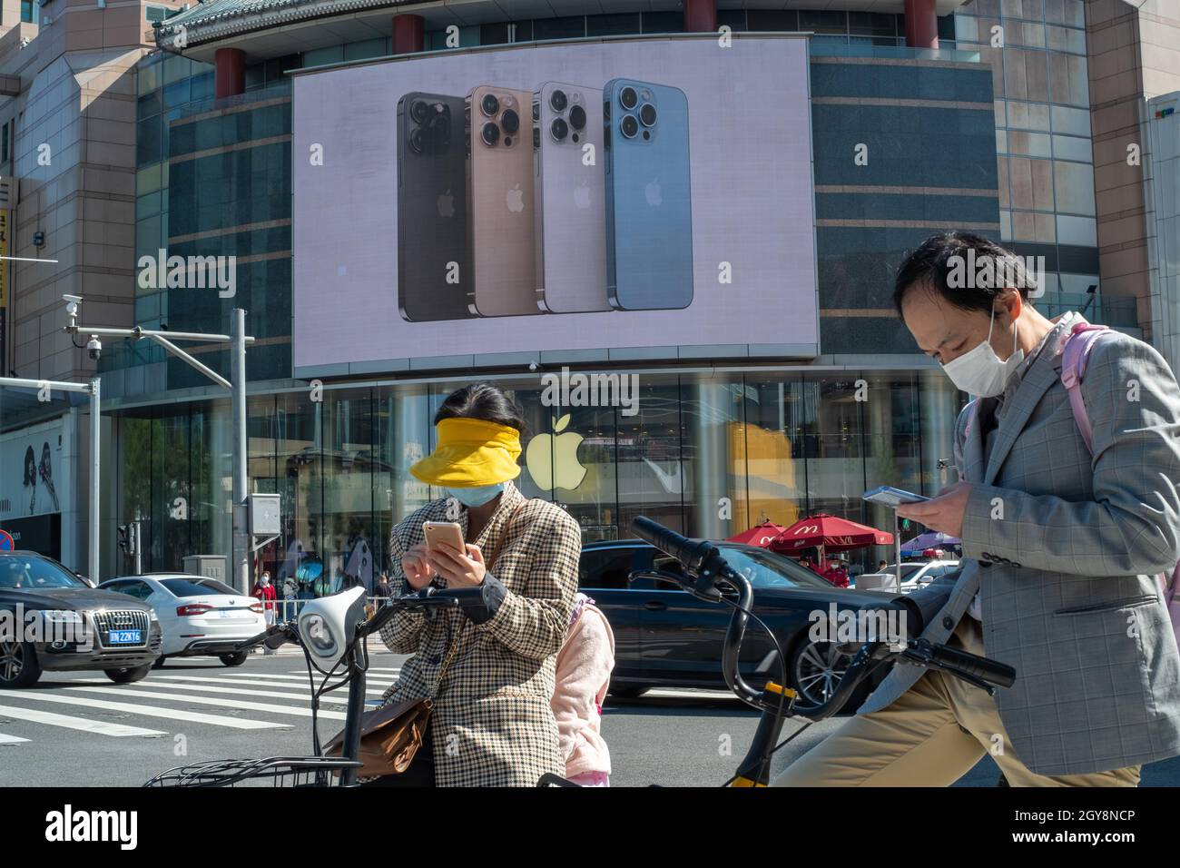 People walk past an Apple store in Wangfujing with iPhone 13 series advertisement on a big screen in Beijing, China. 07-Oct-2021 Stock Photo