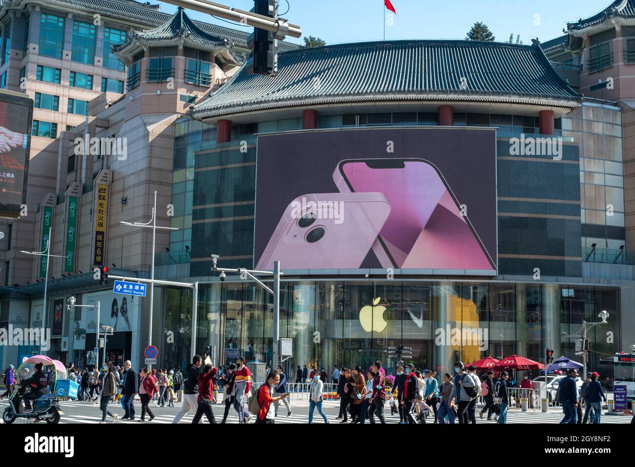 People walk past an apple store in Wangfujing with iPhone 13 series advertisement on a big screen in Beijing, China. 07-Oct-2021 Stock Photo