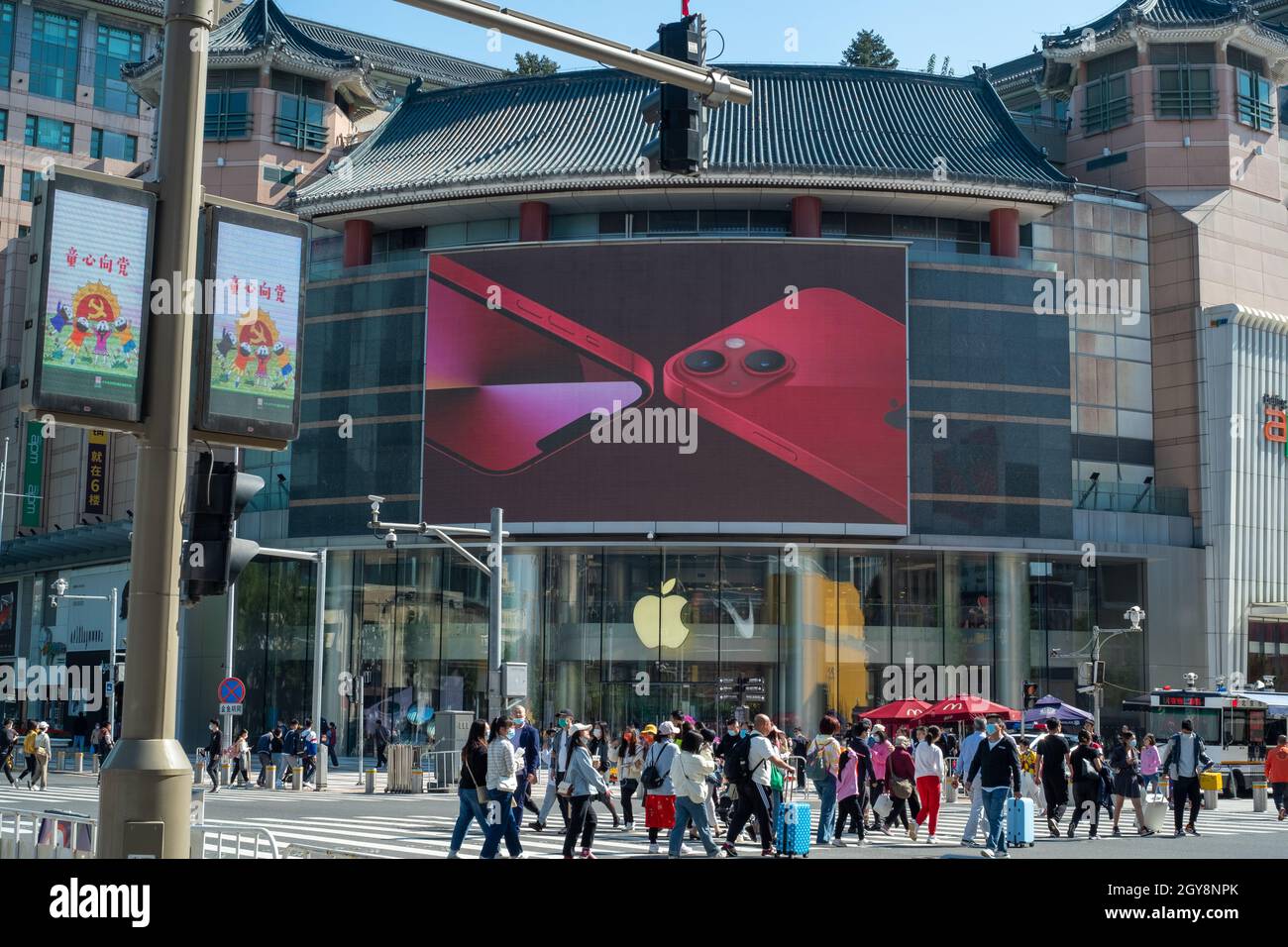 People walk past an apple store in Wangfujing with iPhone 13 series advertisement on a big screen in Beijing, China. 07-Oct-2021 Stock Photo