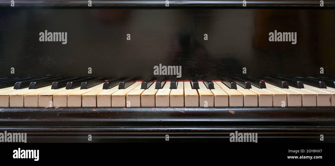 Old black grand piano keyboard with keys from ivory and ebony, part of a musical instrument in