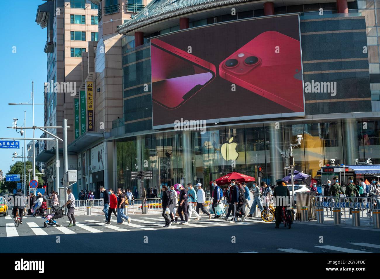 People walk past an apple store in Wangfujing with iPhone 13 series advertisement on a big screen in Beijing, China. 07-Oct-2021 Stock Photo