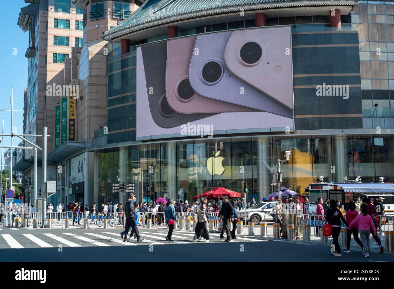 People walk past an apple store in Wangfujing with iPhone 13 series advertisement on a big screen in Beijing, China. 07-Oct-2021 Stock Photo