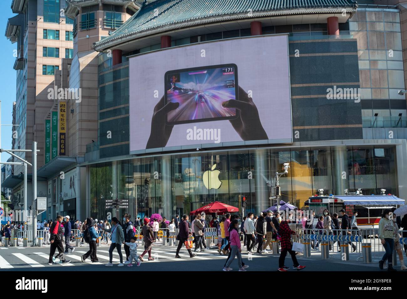 People walk past an apple store in Wangfujing with iPad mini advertisement on a big screen in Beijing, China. 07-Oct-2021 Stock Photo
