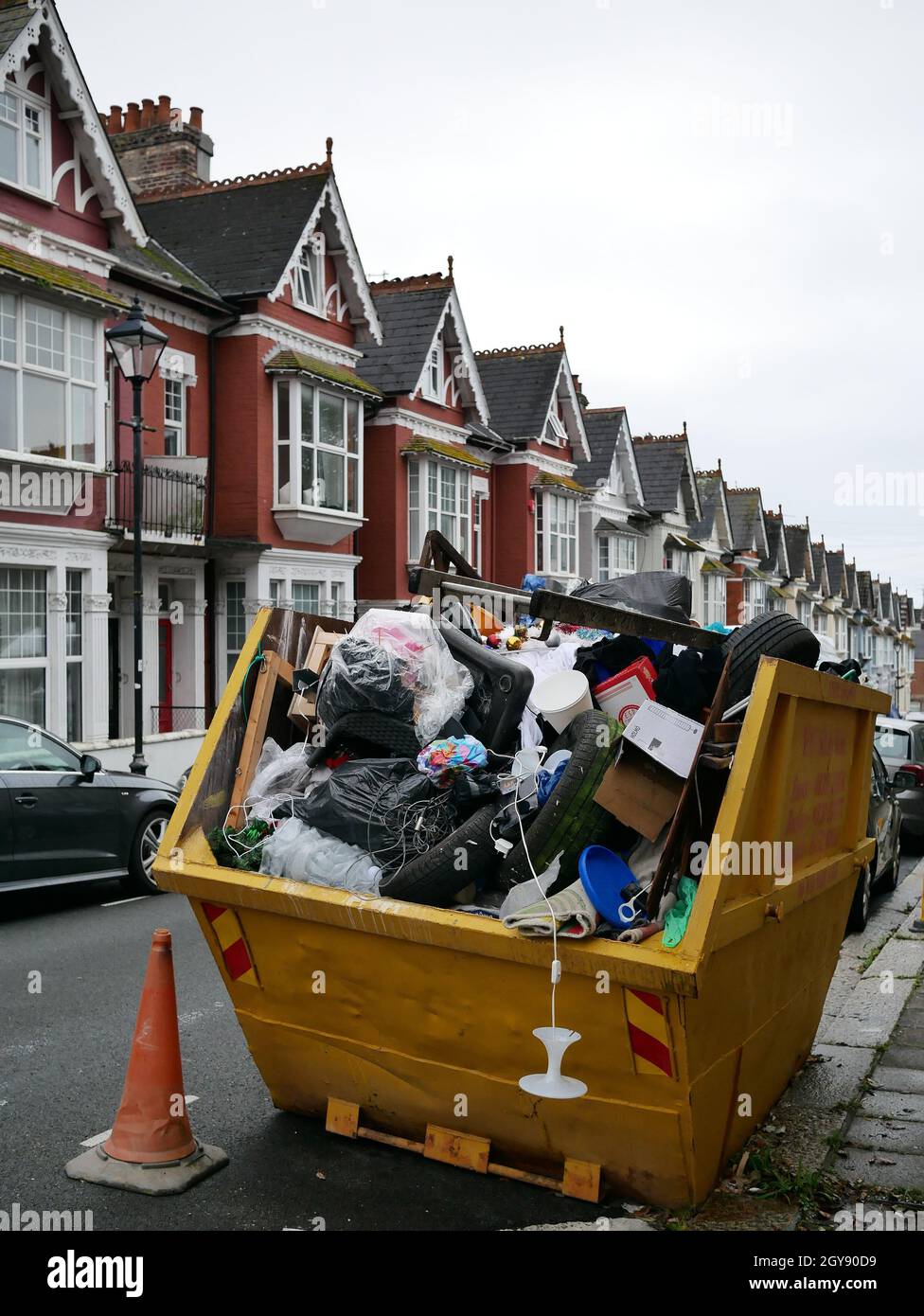 Skip full of rubbish and waste on a residential street. Stock Photo