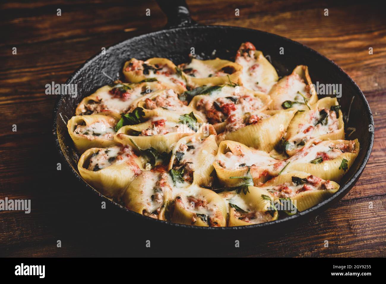 Skillet of baked jumbo shells pasta stuffed with ground beef, spinach