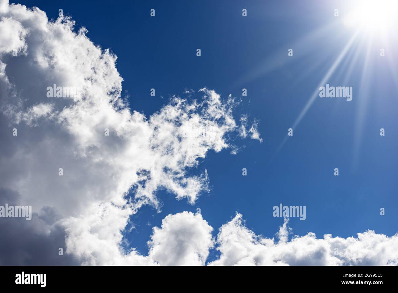 Beautiful blue sky with white cumulus clouds and sun rays. Backlight ...
