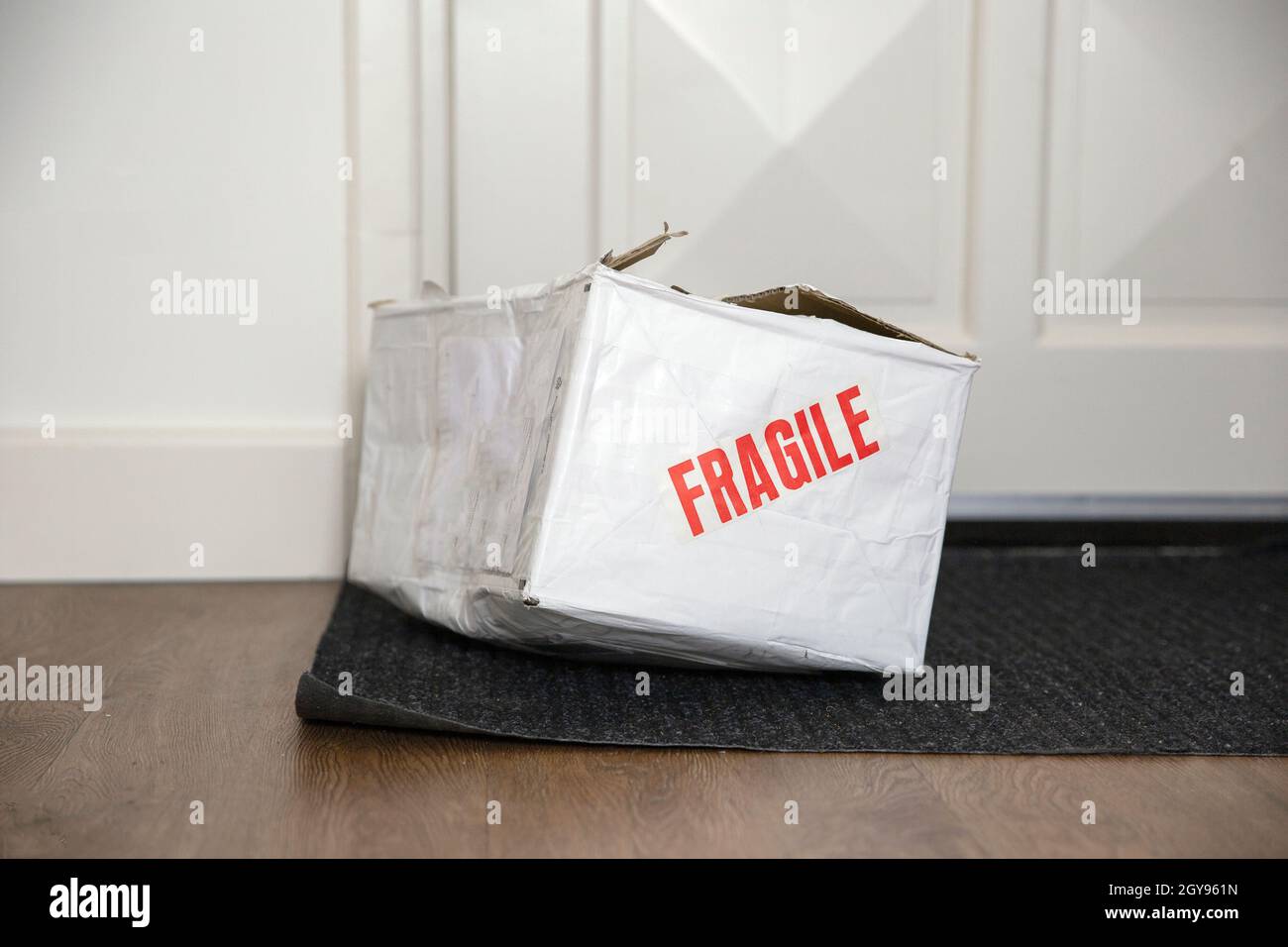 Beat up damaged delivery box with fragile sticker, broken deliverd cardboard packaging at home unhappy Stock Photo