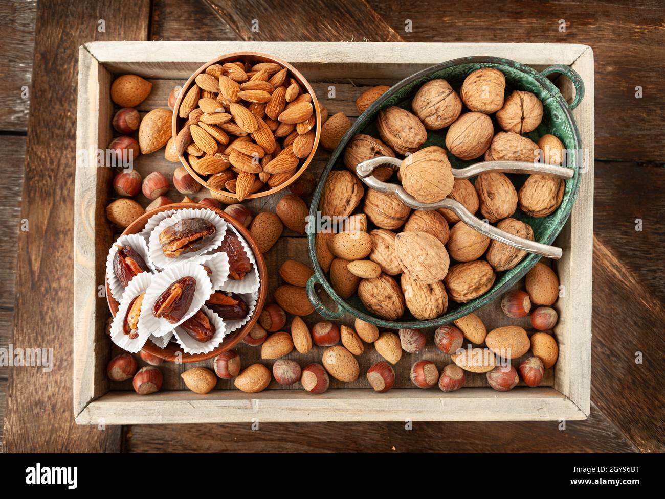 Selection of nuts and dates in rustic wooden tray Stock Photo