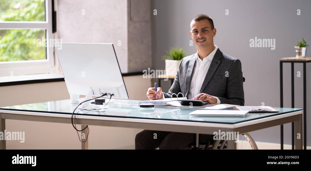 Disabled Accountant In Wheelchair Working Using Computer Stock Photo