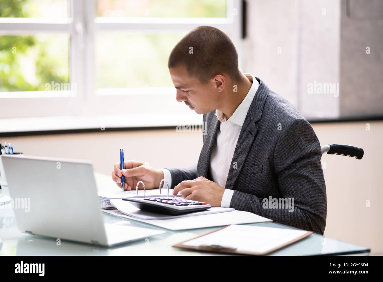 Disabled Accountant In Wheelchair Working Using Computer Stock Photo