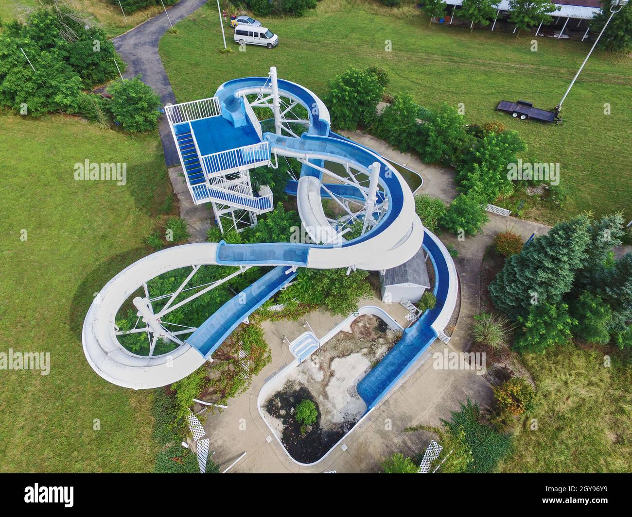 Aerial shot of a blue water slide snaking towards a broken pool