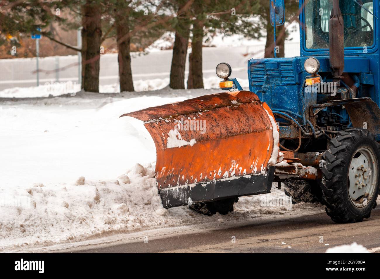 Snowblower tractor clearing snow. Front view of a old blue tractor