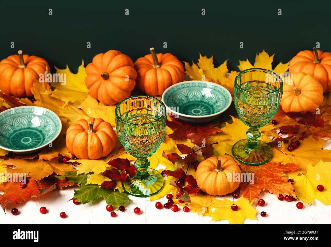 Mockup green vintage plates and goblets, maple leaves, pumpkins and ...