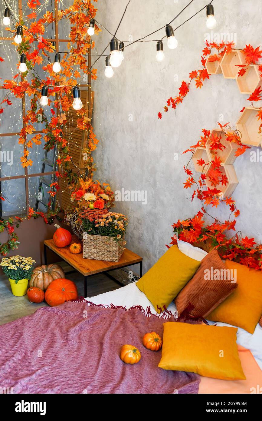 Home autumn decor. Cozy fall bedroom interior bed with orange pillows, flowers, pumpkins, Autumn decoration Stock Photo