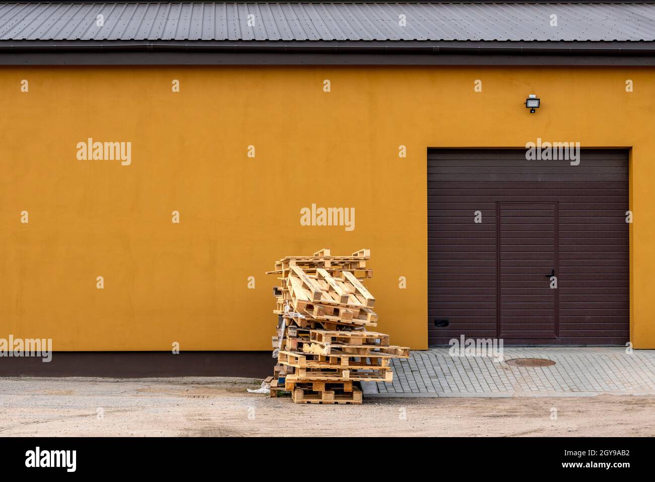 Wood Shipping Pallets Stacked Against Building Garage Door Stock Photo