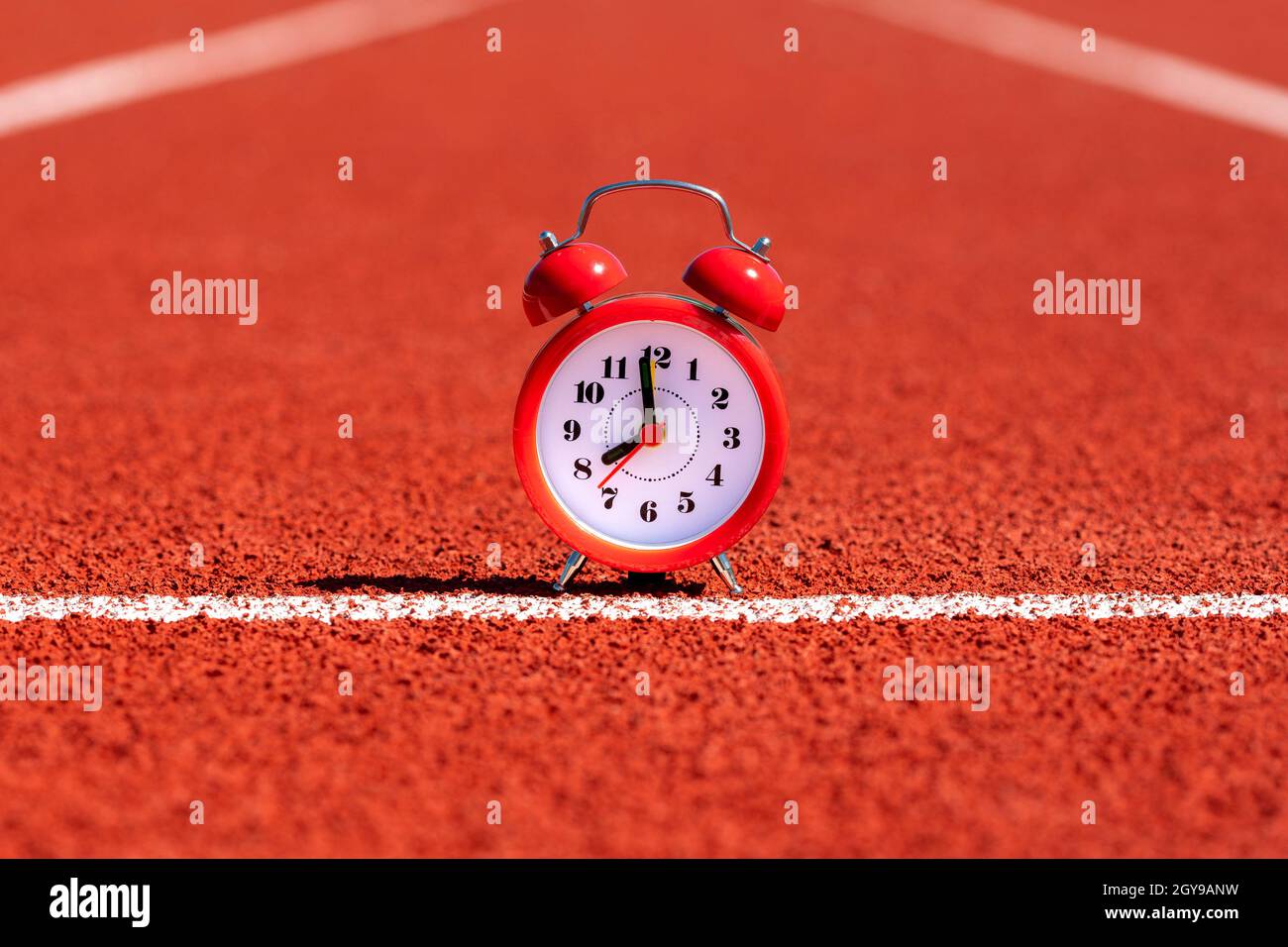 Red alarm clock on to the running track. Starting a business concept. Stock Photo
