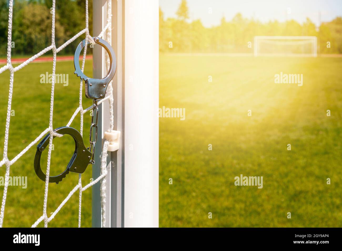 Scam with soccer or football gambling corruption. Handcuffs hanging on the football goals Stock Photo