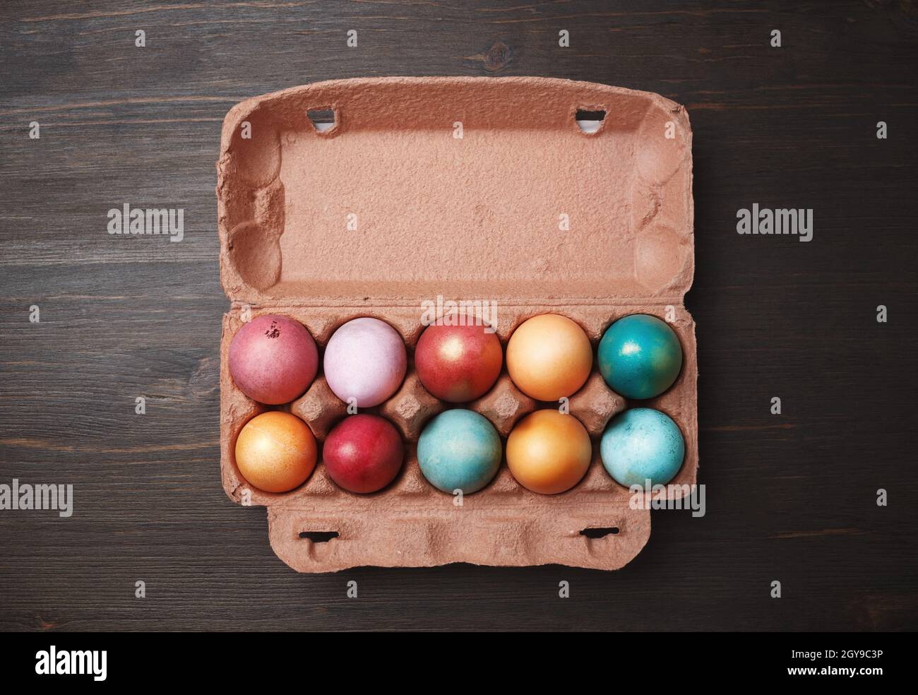 Packaging with colored Easter eggs on wood table background. Flat lay. Stock Photo