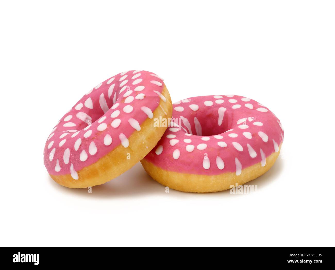 baked round donut with pink icing and white dots isolated on white background, close up Stock Photo