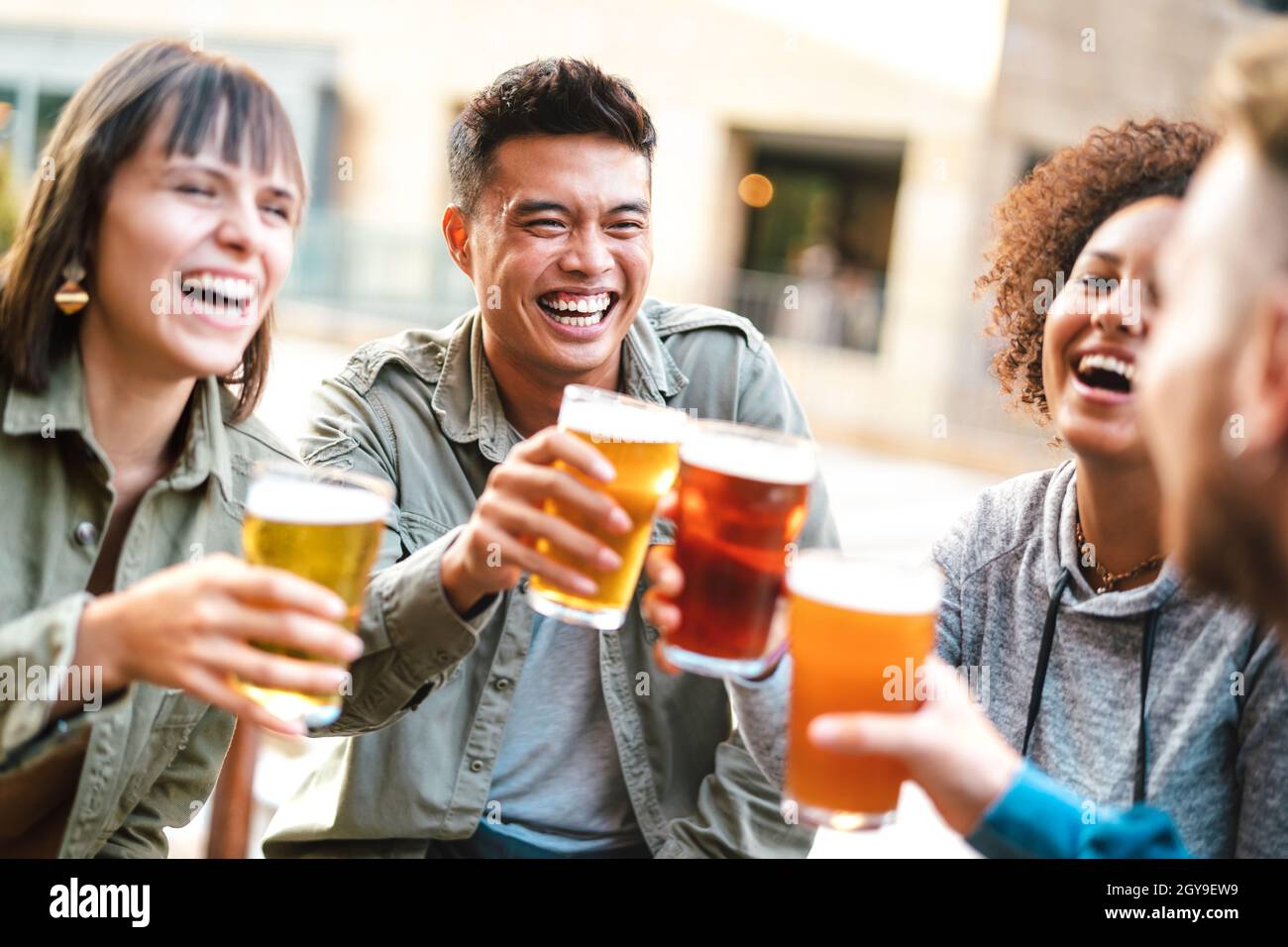 Group of happy multiethnic friends drinking and toasting beer at brewery bar restaurant - Beverage concept with men and women having fun together Stock Photo