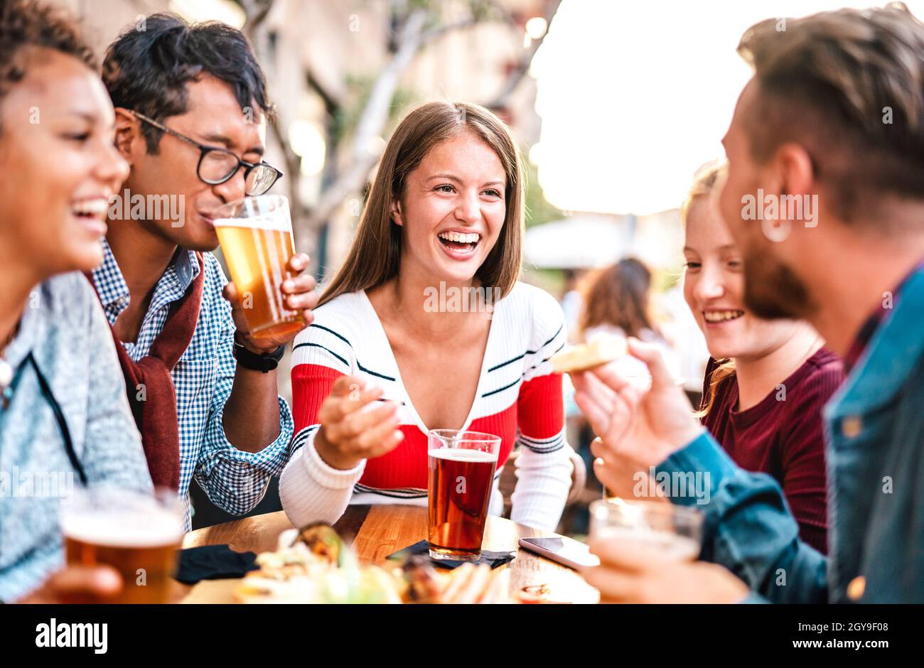 Multicultural people drinking beer at brewery bar garden - Genuine friendship life style concept with men and women spending happy hour together Stock Photo