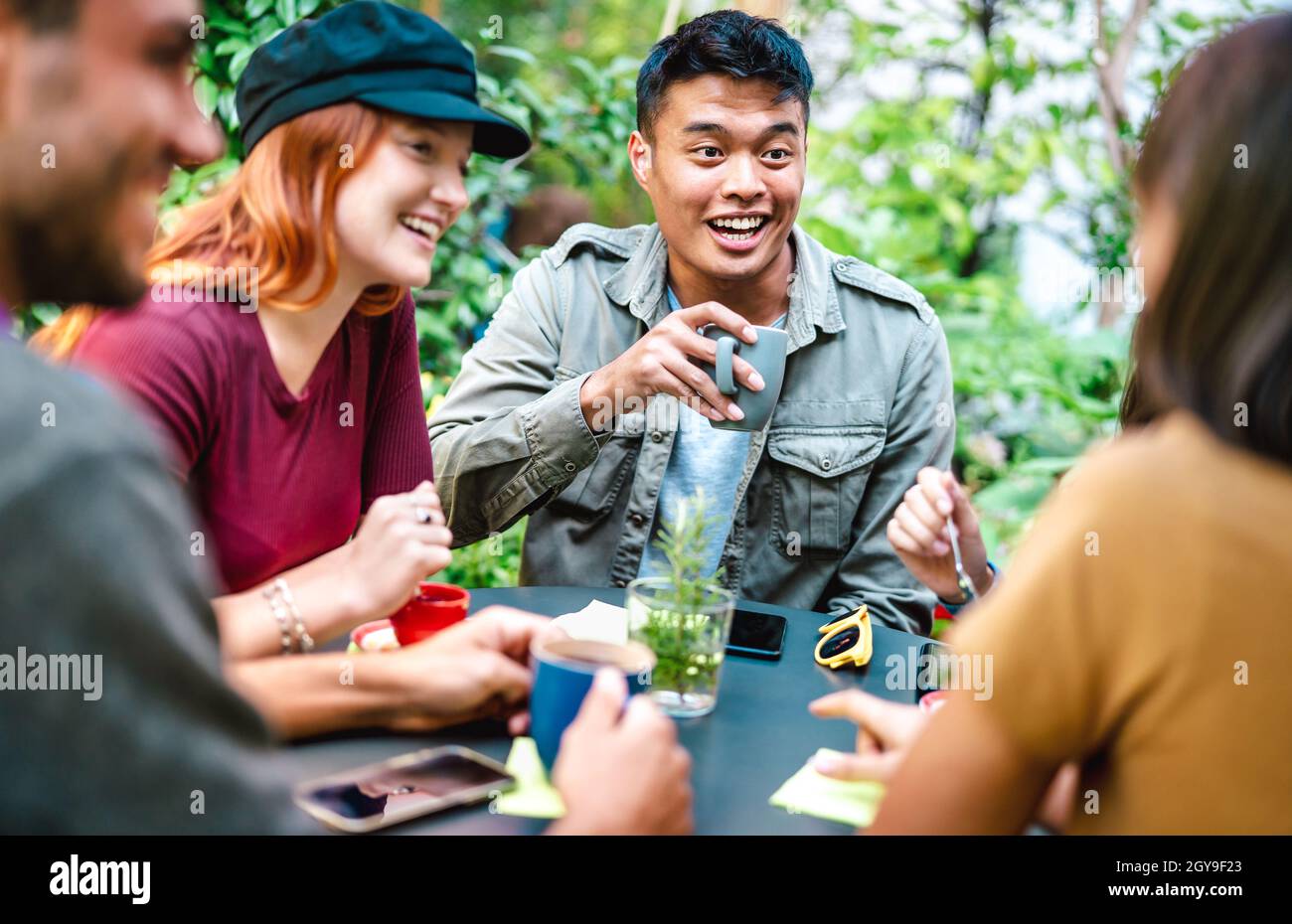 People group drinking latte at coffee bar garden - Happy friends talking and having fun together at hostel dehors - Life style concept Stock Photo