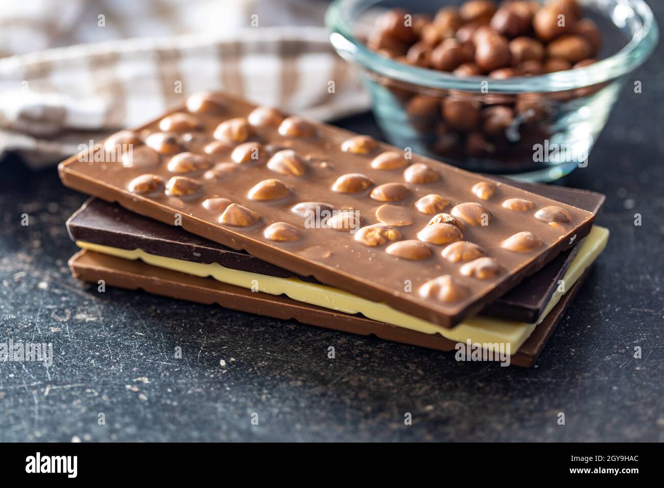 Various chocolate bars with hazelnuts on black table. Stock Photo