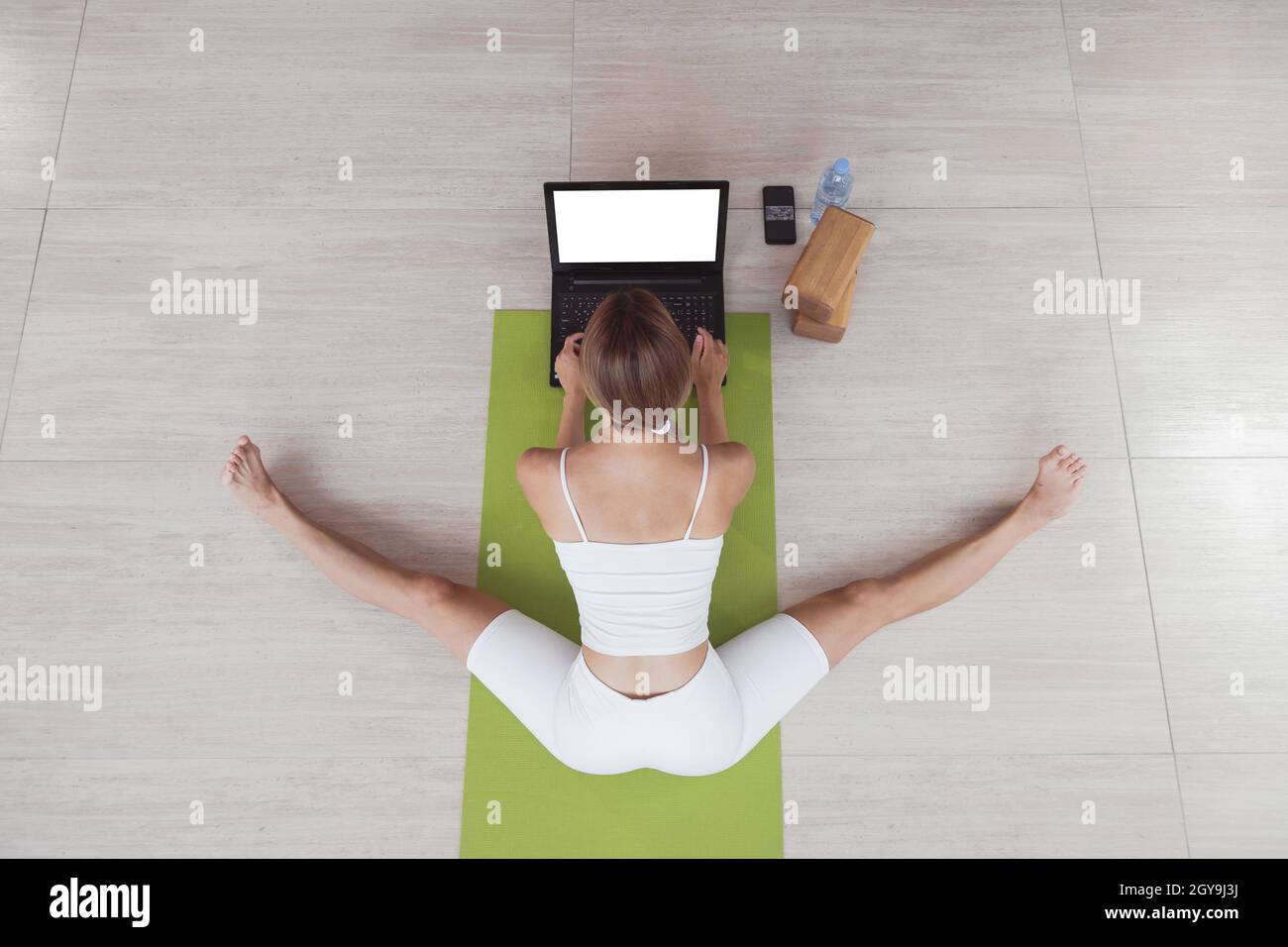 Young fit woman in sportswear doing sport or yoga online with laptop. Remote workouts, online trainer. Top view. Laptop with blank screen Stock Photo