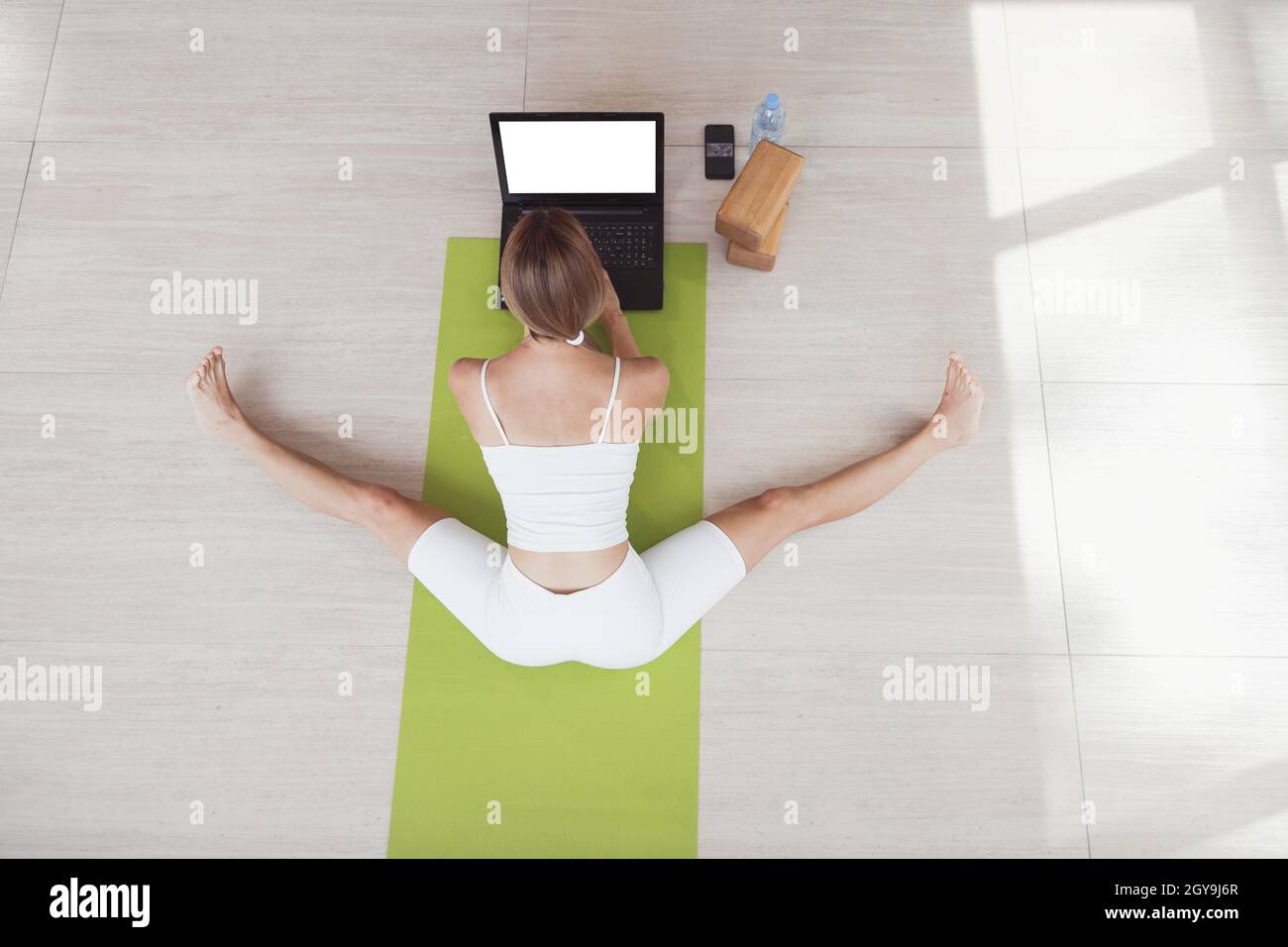 Young fit woman in sportswear doing sport or yoga online with laptop. Remote workouts, online trainer. Top view. Laptop with blank screen Stock Photo