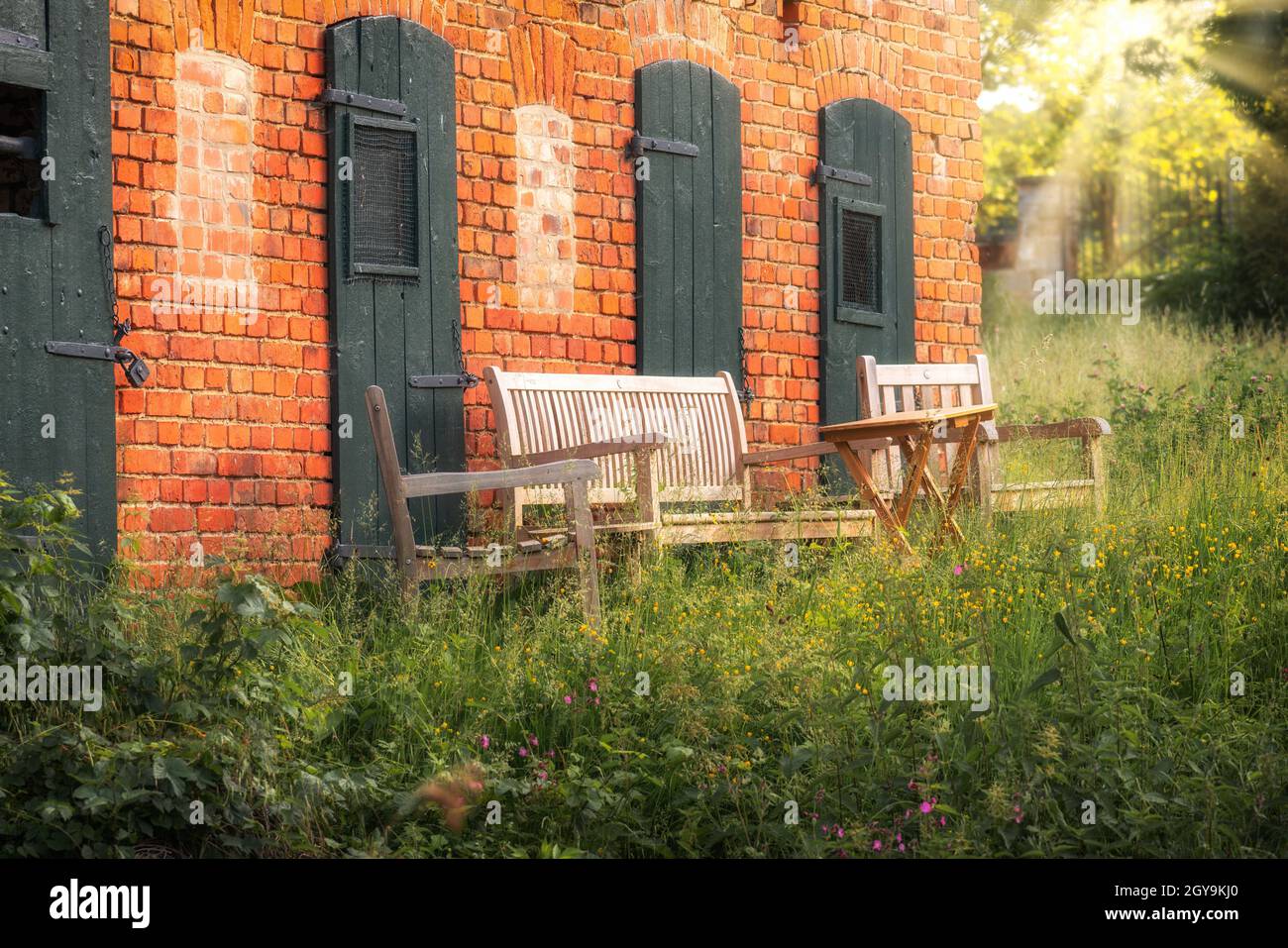 Wooden sofa set on the terrace in front of a red brick house in summer Stock Photo