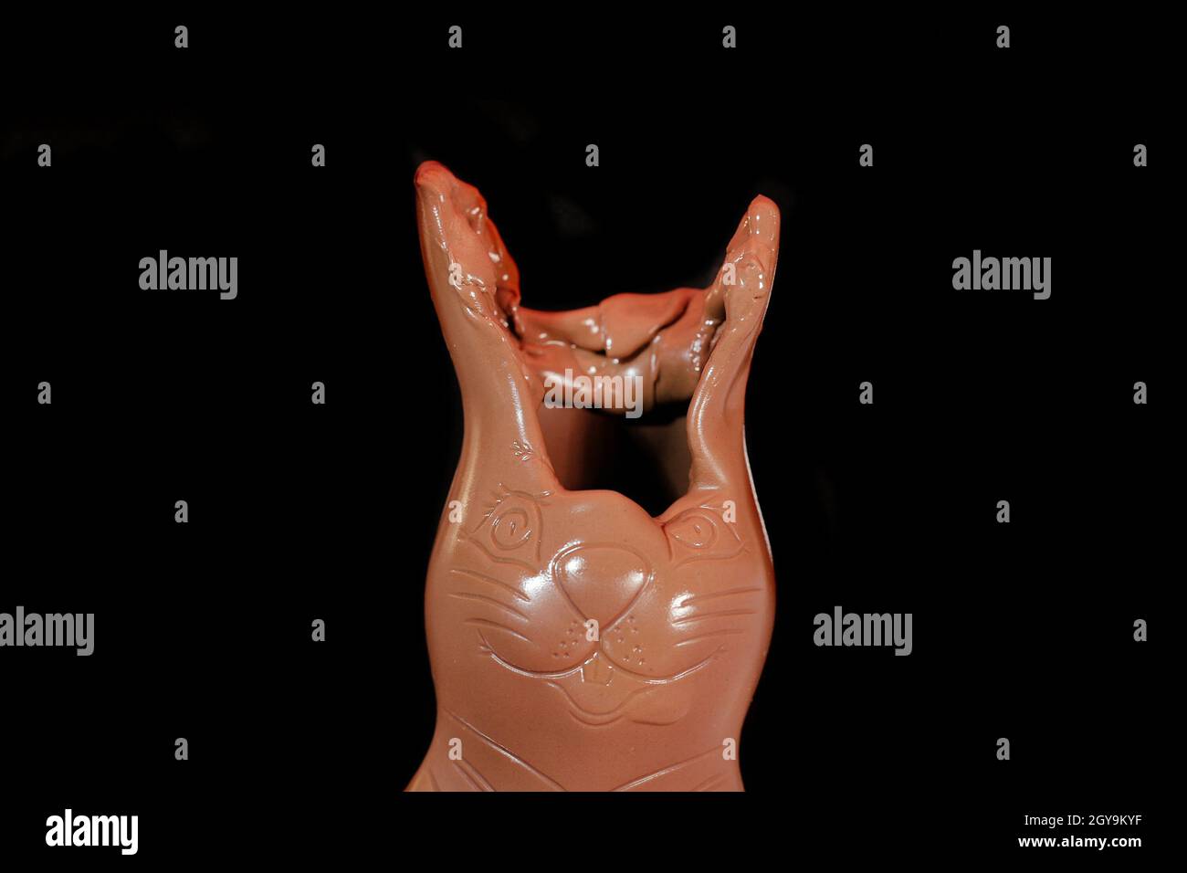 Chocolate bunny figure melting in heat, face slowly melting down, dark background, chocolate rabbit with big ears Stock Photo