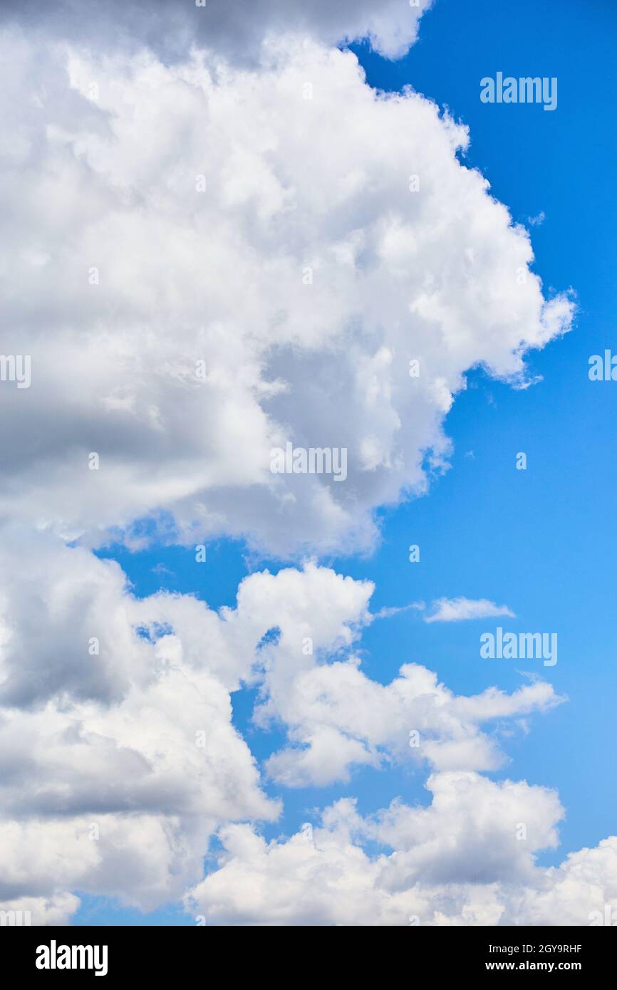 Puffy white clouds with a hint of darkness on a blue sky day Stock Photo
