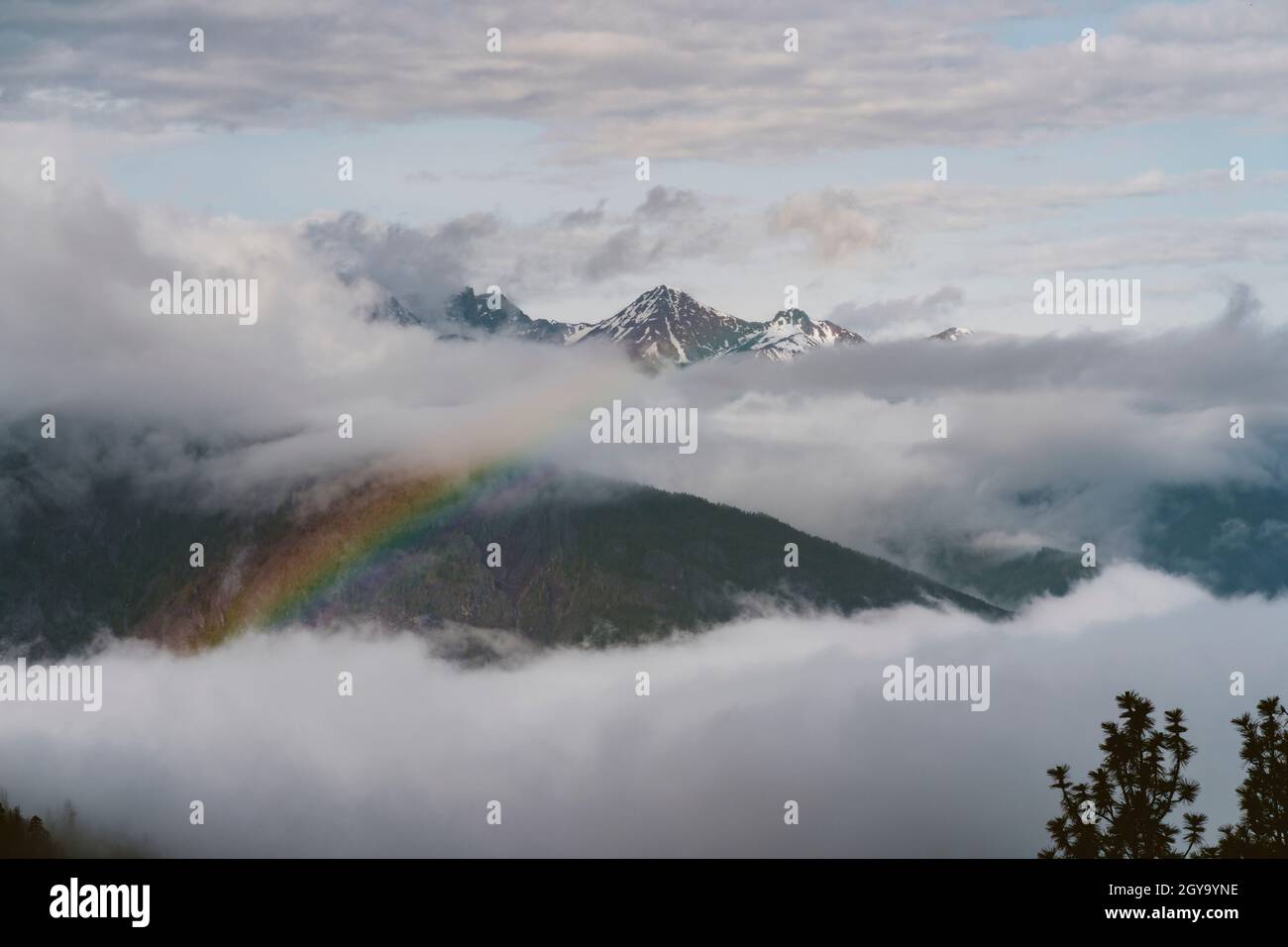 A rainbow appears in the clouds after a rain storm in the mountains ...